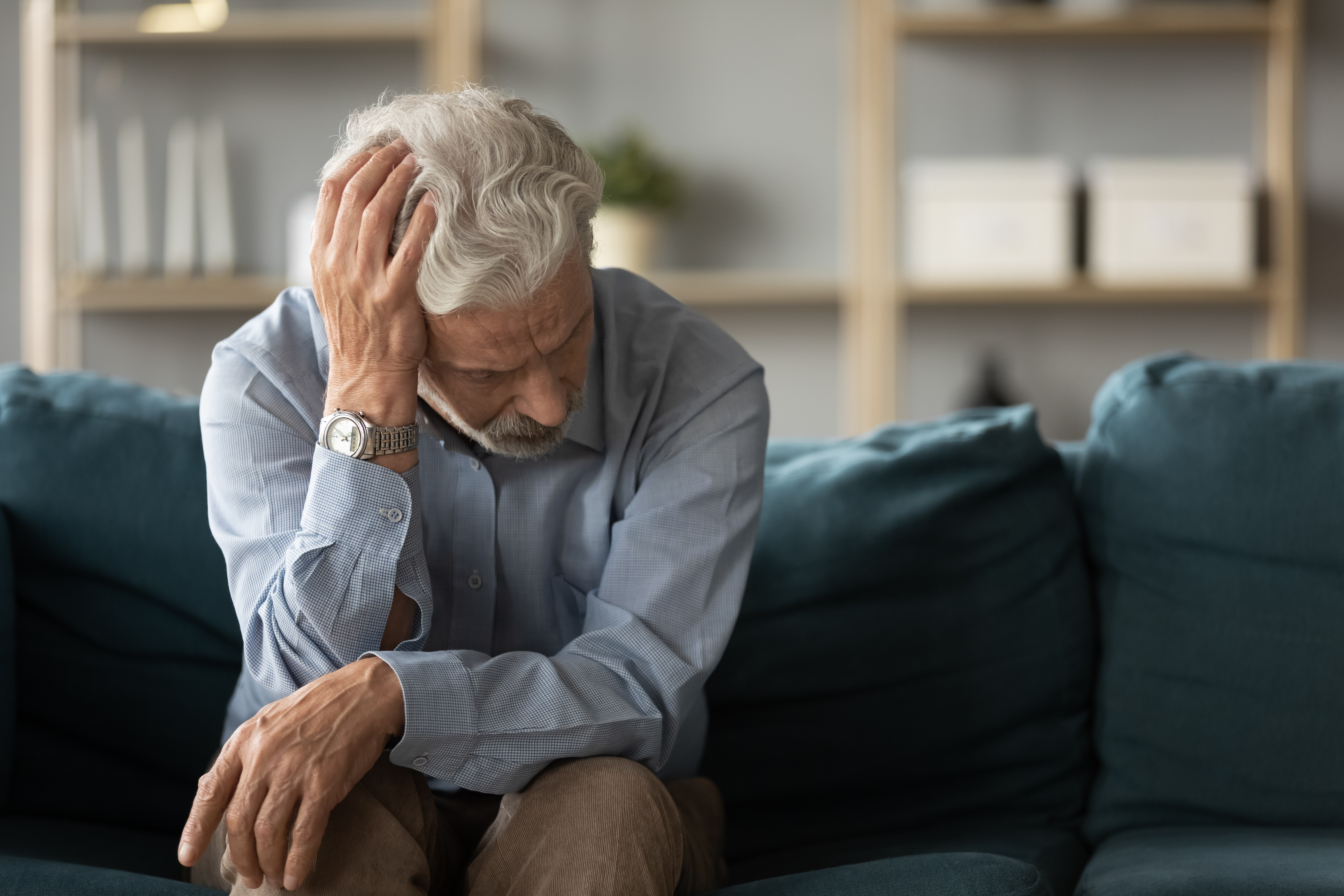 An old man holding his head looking upset | Source: Shutterstock