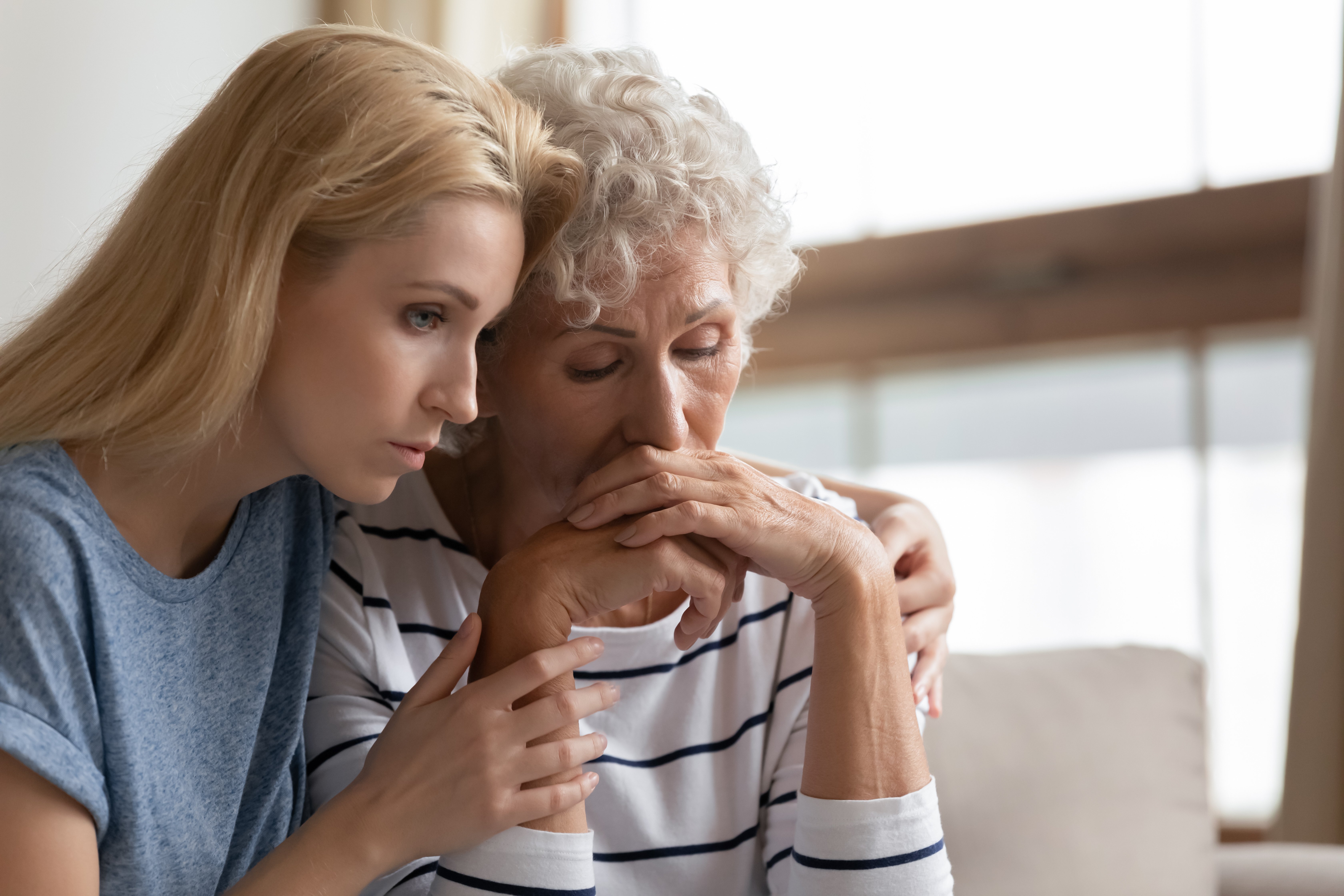 A young woman comforting an older lady | Source: Shutterstock