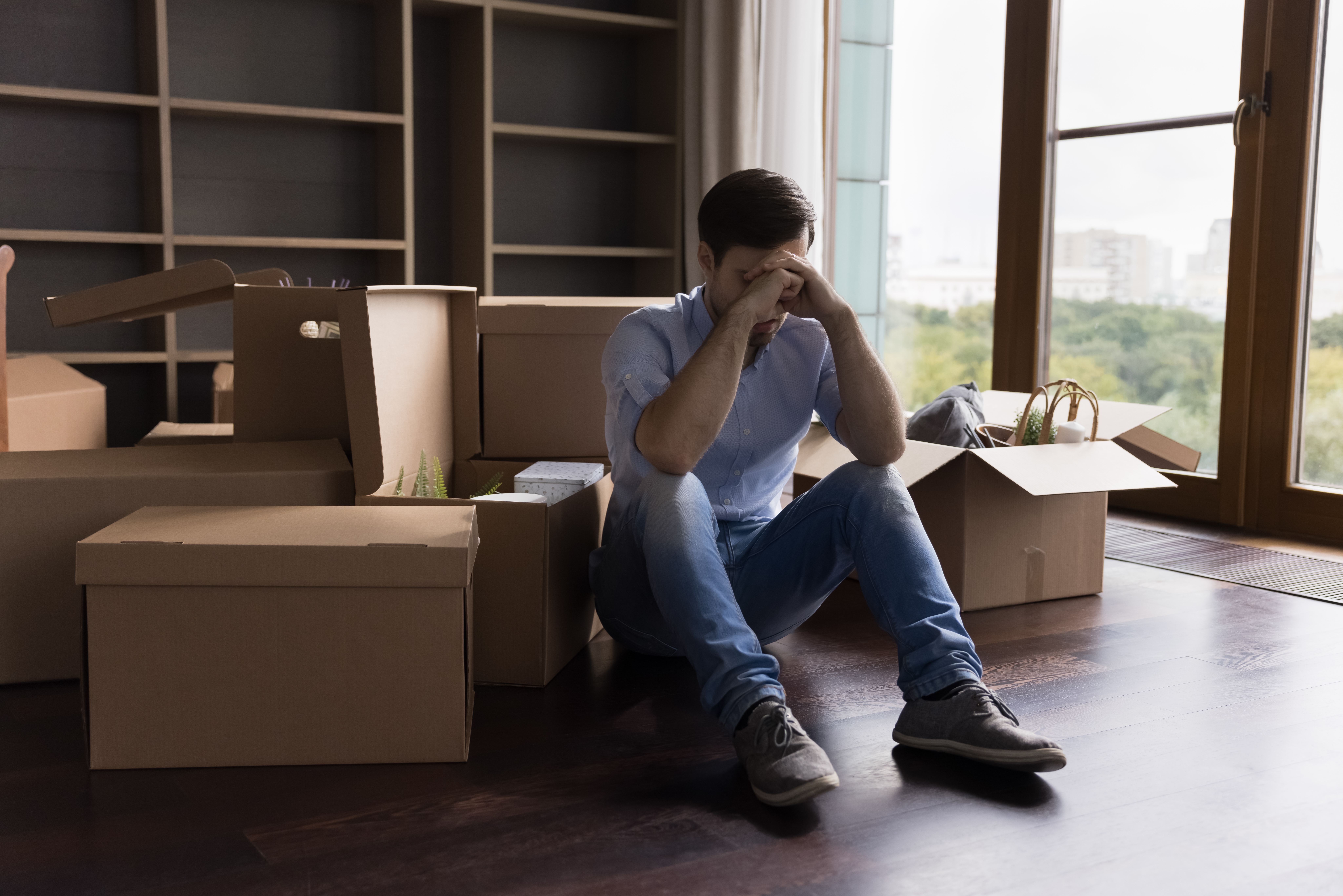 A young man sitting on the floor surrounded by moving boxes | Sources: Shutterstock